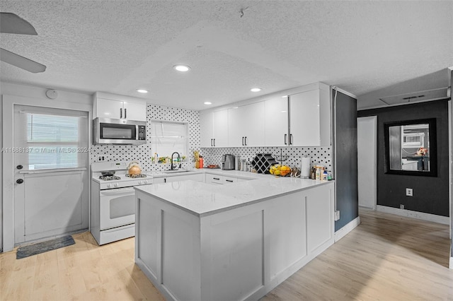 kitchen with white range with gas cooktop, light wood-type flooring, a textured ceiling, sink, and white cabinets