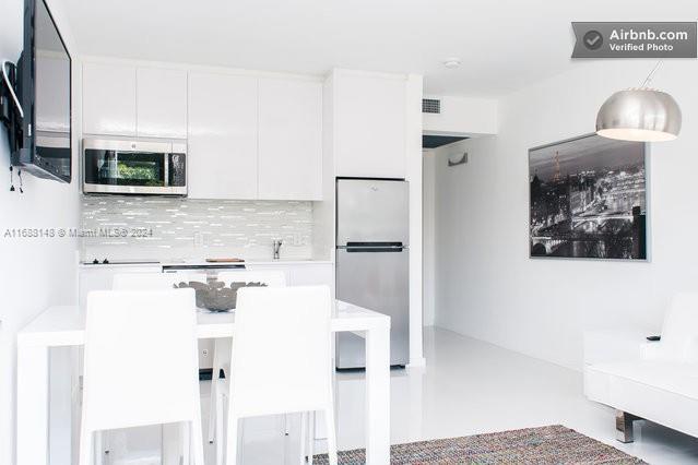 kitchen with white cabinetry, appliances with stainless steel finishes, pendant lighting, and backsplash