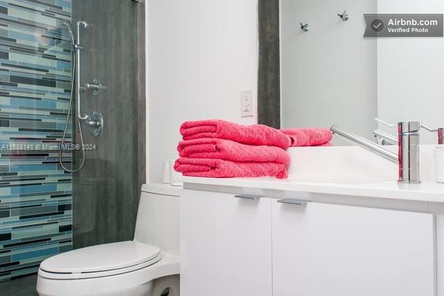 bathroom featuring toilet, vanity, and a tile shower