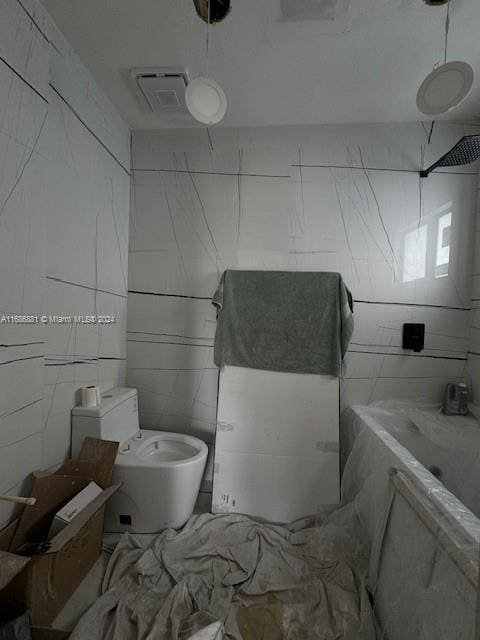 bathroom featuring toilet and tile walls