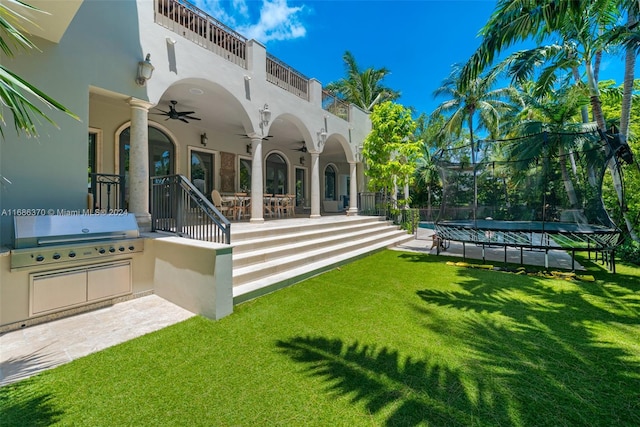 rear view of property featuring a patio, a lawn, ceiling fan, and a balcony