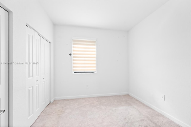 unfurnished bedroom with light colored carpet and a closet