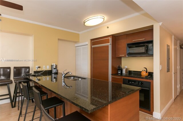 kitchen with black appliances, sink, kitchen peninsula, crown molding, and light hardwood / wood-style flooring