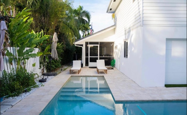 view of swimming pool with a sunroom and a patio