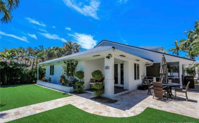 rear view of property featuring a lawn and a patio