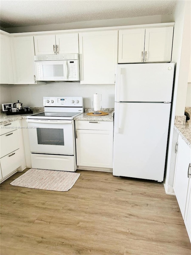 kitchen with white cabinetry, light hardwood / wood-style floors, and white appliances