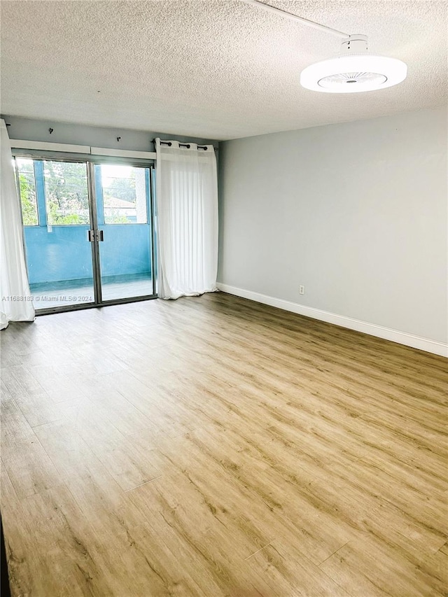 unfurnished room featuring a textured ceiling and light hardwood / wood-style flooring