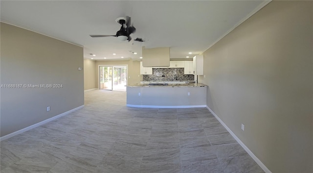 kitchen featuring kitchen peninsula, ornamental molding, ceiling fan, light stone countertops, and white cabinetry