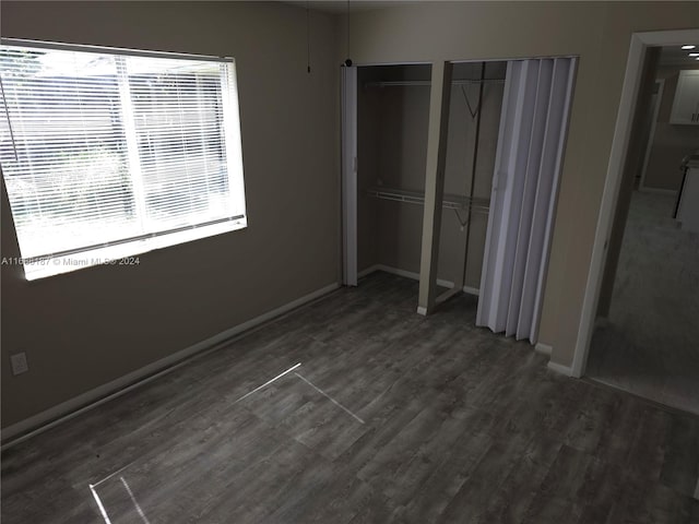 unfurnished bedroom with two closets and dark hardwood / wood-style floors