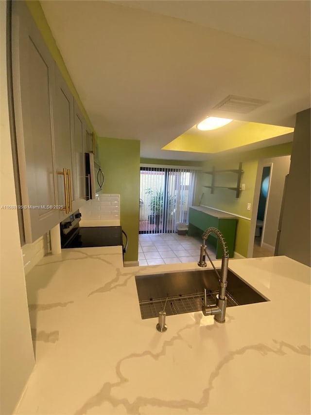 kitchen with a tray ceiling, sink, electric range, and light stone countertops