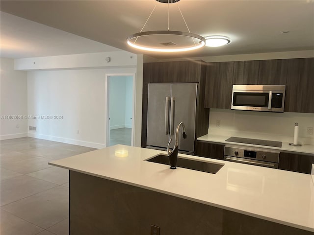 kitchen with dark brown cabinetry, stainless steel appliances, sink, and light tile patterned flooring