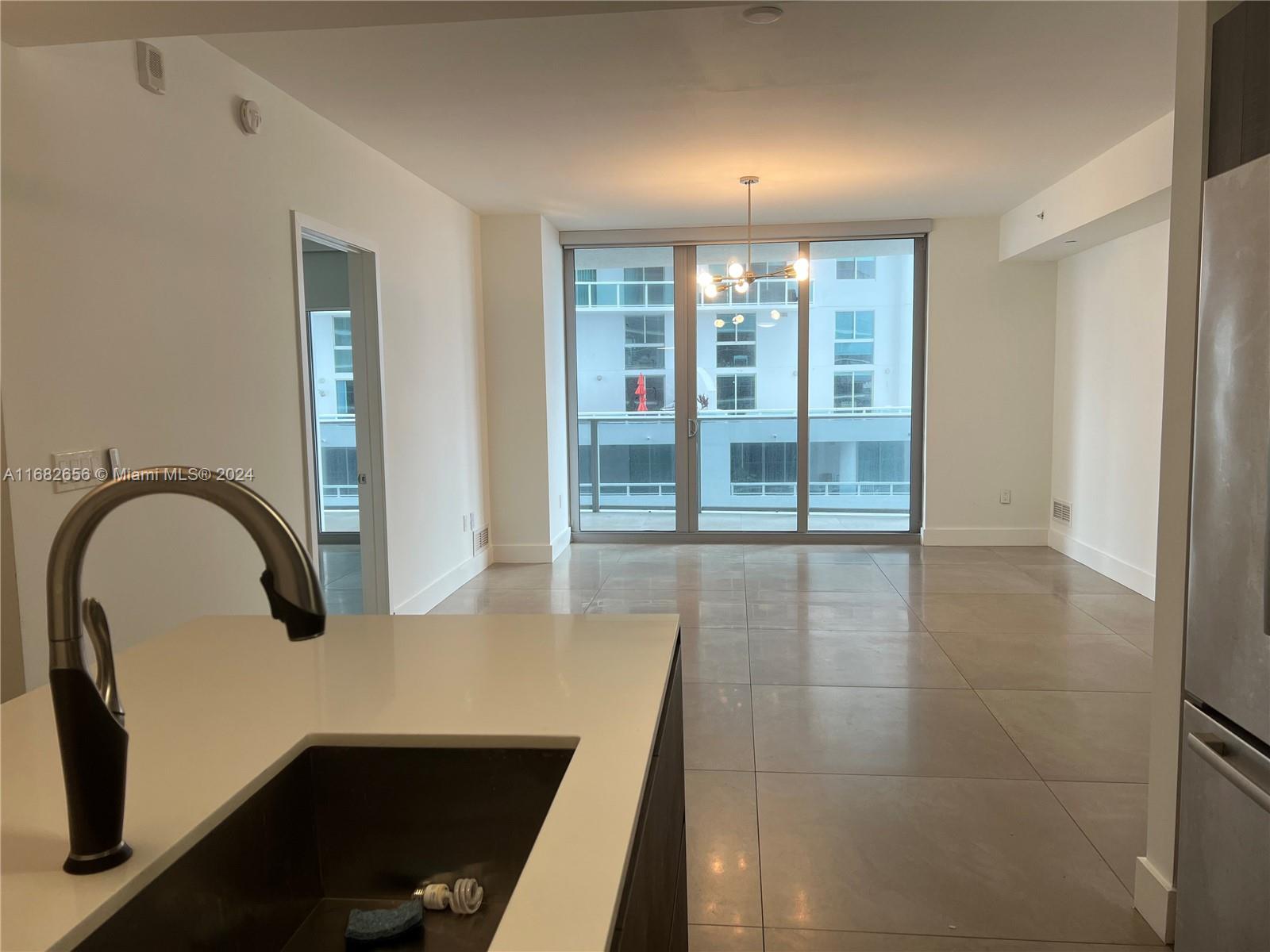 kitchen with a notable chandelier, light tile patterned floors, pendant lighting, floor to ceiling windows, and sink