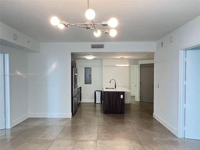 kitchen with a center island with sink, sink, an inviting chandelier, decorative light fixtures, and stainless steel fridge