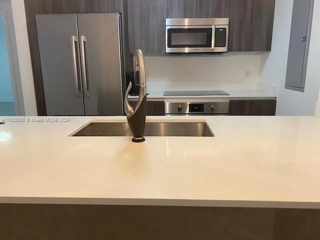 kitchen featuring electric panel, appliances with stainless steel finishes, sink, and dark brown cabinets