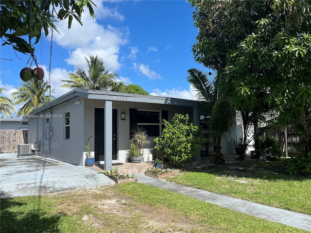 view of front of home featuring a front yard, a patio, and cooling unit