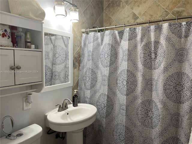 bathroom with a shower with shower curtain, toilet, and sink