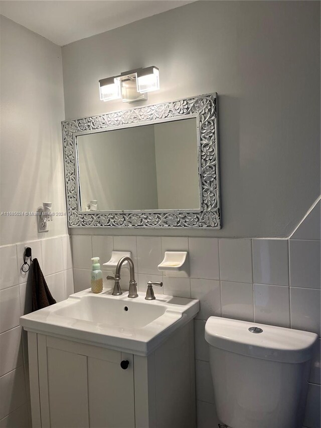 bathroom featuring vanity, toilet, and tile walls