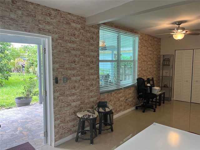 interior space with beam ceiling, ceiling fan, and brick wall