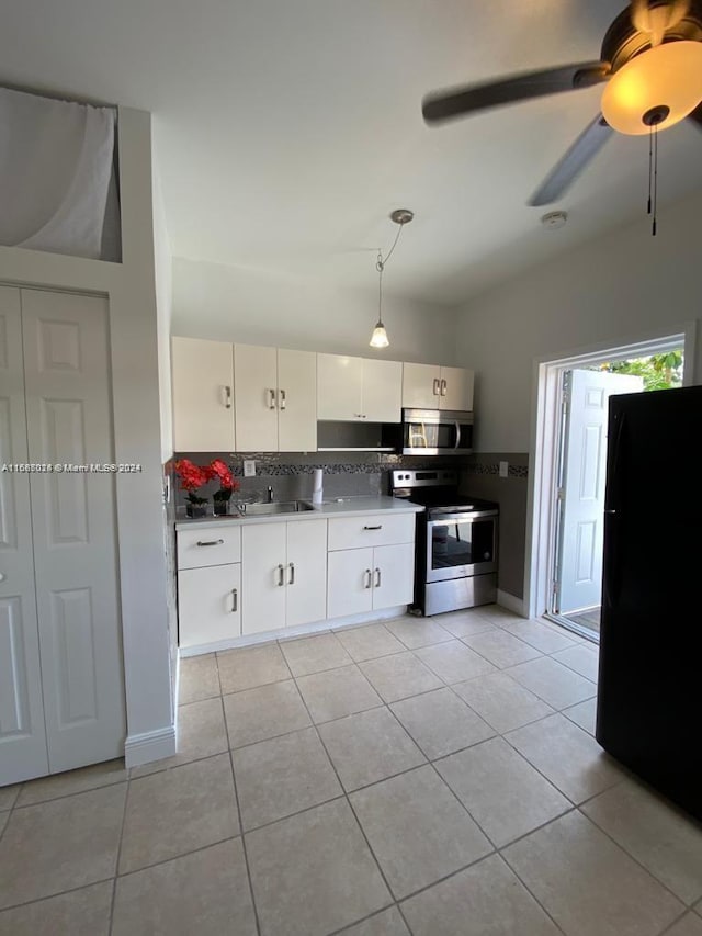 kitchen featuring hanging light fixtures, light tile patterned floors, appliances with stainless steel finishes, tasteful backsplash, and white cabinetry