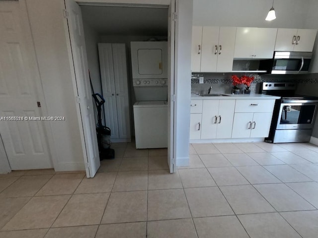 kitchen featuring white cabinets, sink, stacked washer and dryer, hanging light fixtures, and appliances with stainless steel finishes