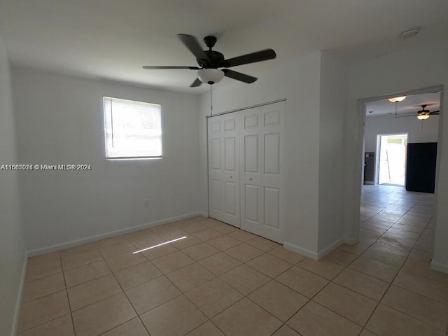 unfurnished bedroom with ceiling fan, a closet, and light tile patterned floors