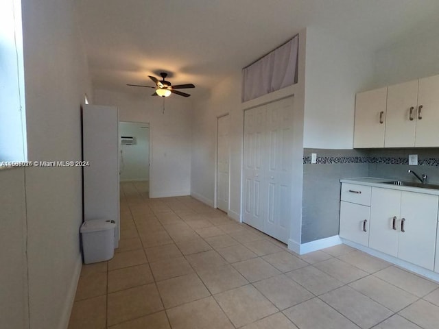 kitchen featuring decorative backsplash, ceiling fan, sink, light tile patterned floors, and white cabinetry