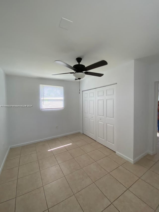 unfurnished bedroom with light tile patterned floors, a closet, and ceiling fan