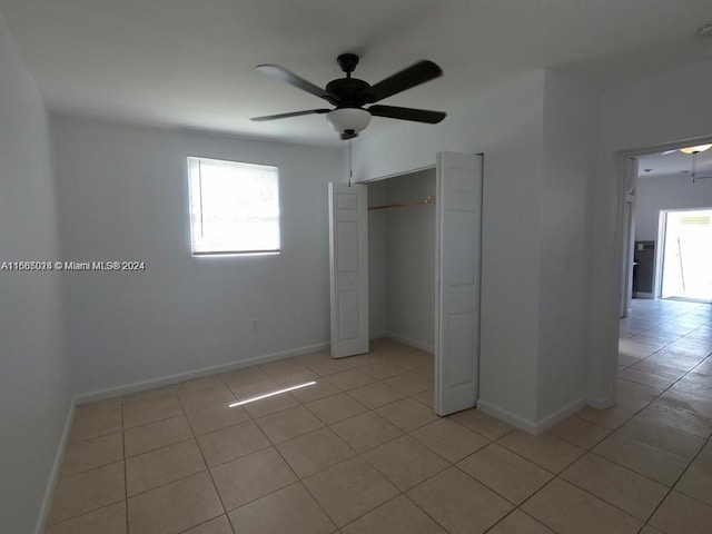 unfurnished bedroom with ceiling fan, light tile patterned floors, and a closet