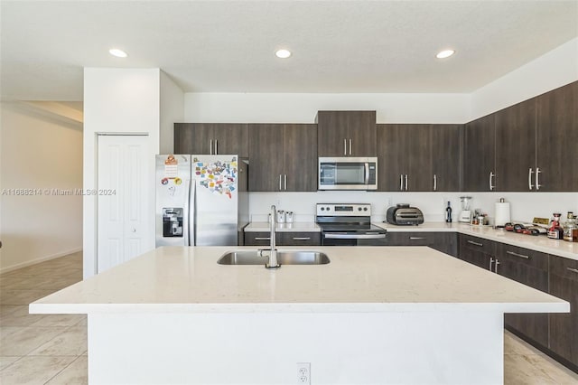 kitchen featuring dark brown cabinets, appliances with stainless steel finishes, sink, and an island with sink