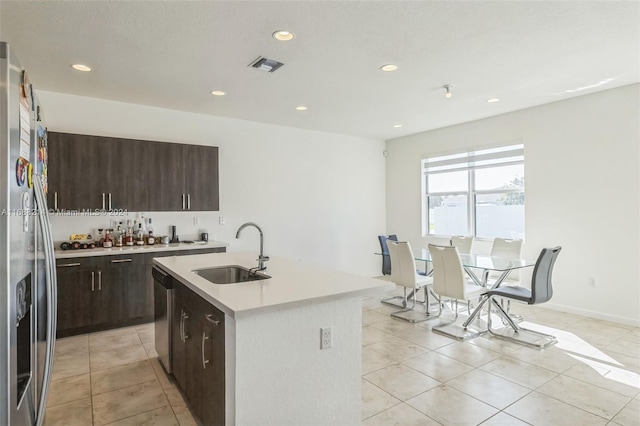 kitchen featuring dark brown cabinetry, a center island with sink, sink, and appliances with stainless steel finishes