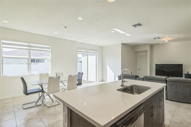 kitchen featuring an island with sink, stainless steel dishwasher, a healthy amount of sunlight, and sink