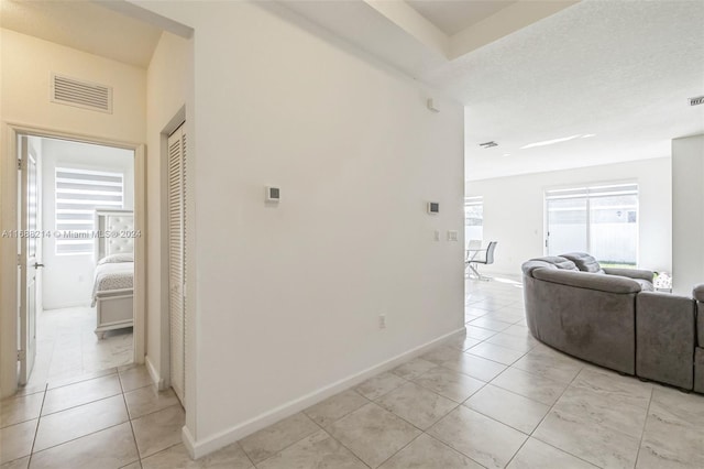 hall with a textured ceiling and light tile patterned floors