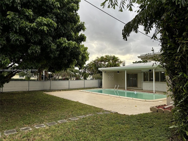 view of swimming pool with ceiling fan, a patio area, and a lawn