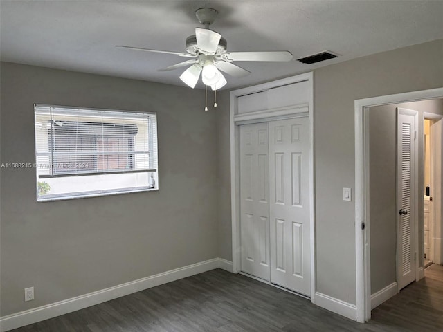 unfurnished bedroom with dark hardwood / wood-style flooring, ceiling fan, and a closet