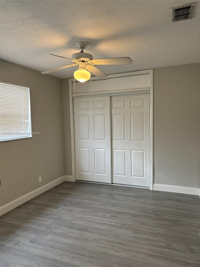 unfurnished bedroom with ceiling fan, a closet, and hardwood / wood-style flooring