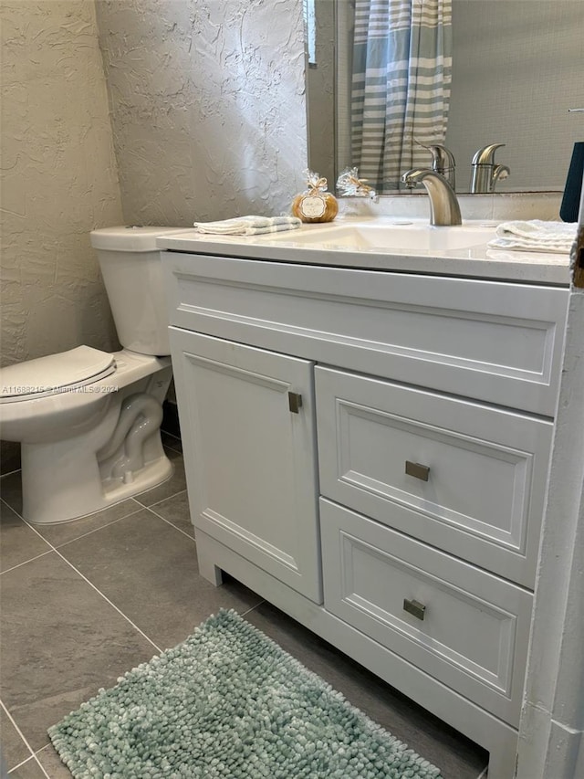 bathroom featuring tile patterned flooring, vanity, and toilet