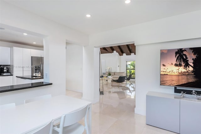 kitchen featuring white cabinetry, dark stone counters, beamed ceiling, and stainless steel refrigerator with ice dispenser