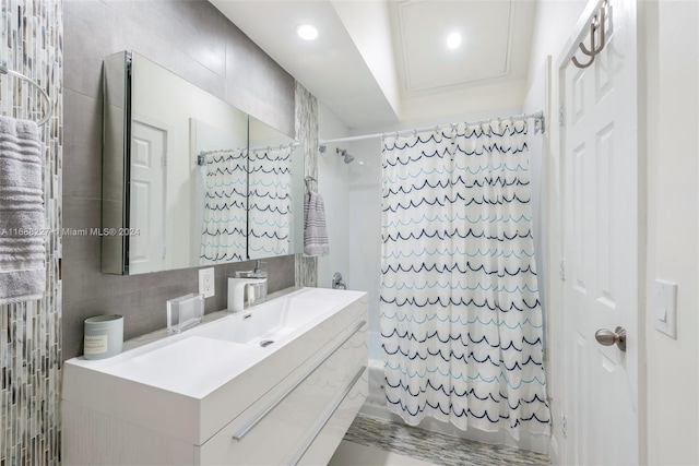 bathroom featuring vanity, backsplash, shower / bath combination with curtain, and tile walls