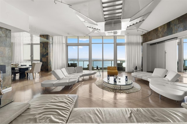 living room featuring a high ceiling, wood-type flooring, a water view, and expansive windows