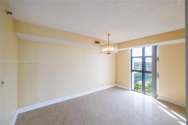 empty room featuring a textured ceiling and an inviting chandelier