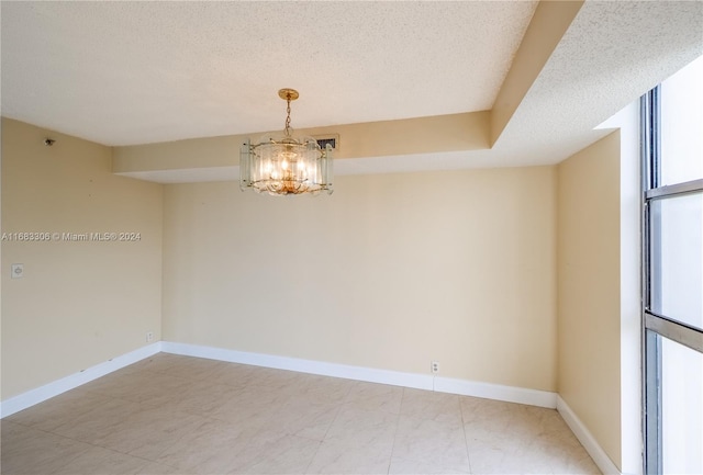 spare room featuring a textured ceiling and a chandelier