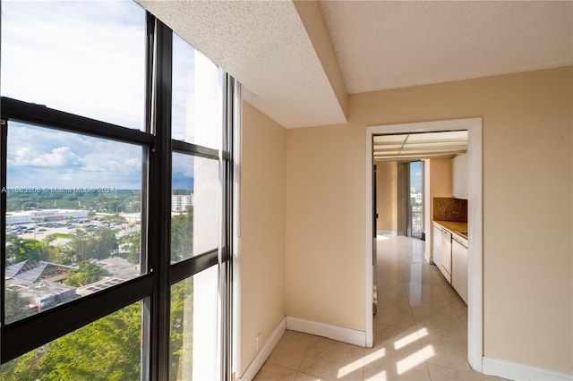 corridor with expansive windows, plenty of natural light, light tile patterned floors, and a textured ceiling