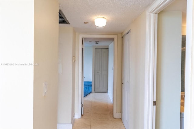 hallway featuring a textured ceiling and light tile patterned floors