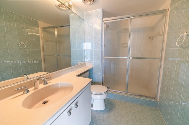 bathroom featuring toilet, vanity, tile patterned flooring, and a shower with shower door