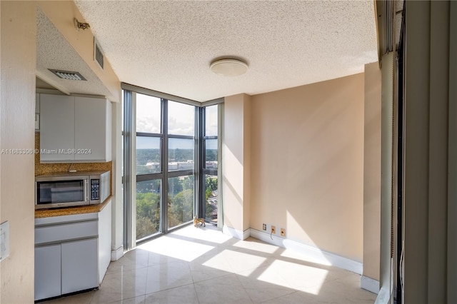 tiled spare room featuring expansive windows, a wealth of natural light, and a textured ceiling