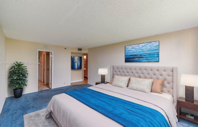 bedroom with ensuite bathroom, light carpet, and a textured ceiling