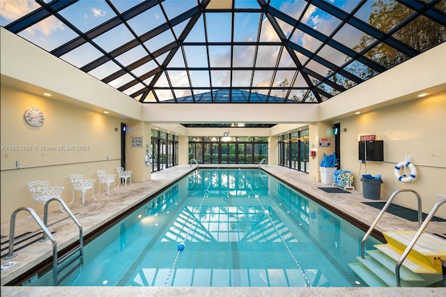 pool at dusk with glass enclosure and a patio