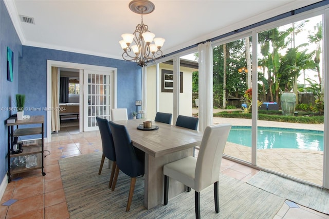 dining area featuring tile patterned flooring, ornamental molding, and a notable chandelier