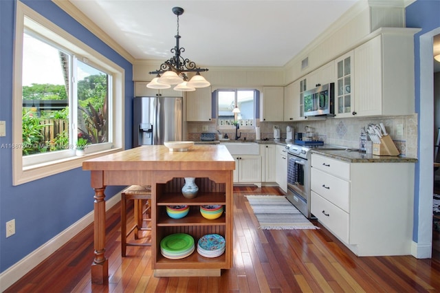 kitchen featuring dark hardwood / wood-style flooring, light stone counters, decorative backsplash, white cabinetry, and appliances with stainless steel finishes