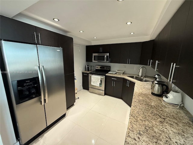 kitchen featuring stainless steel appliances, sink, light tile patterned floors, and light stone counters